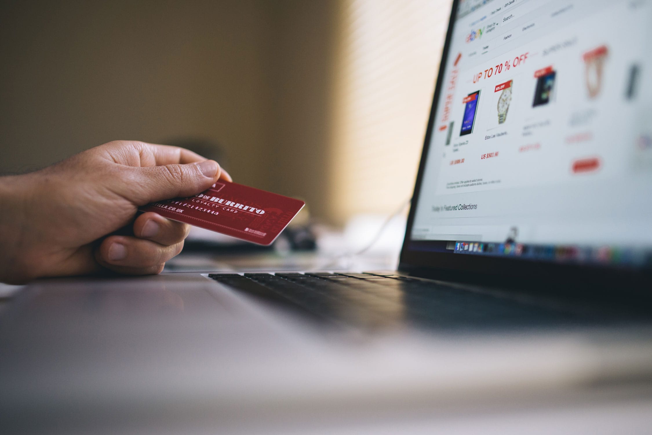 A woman holding a credit card while shopping online on eBay