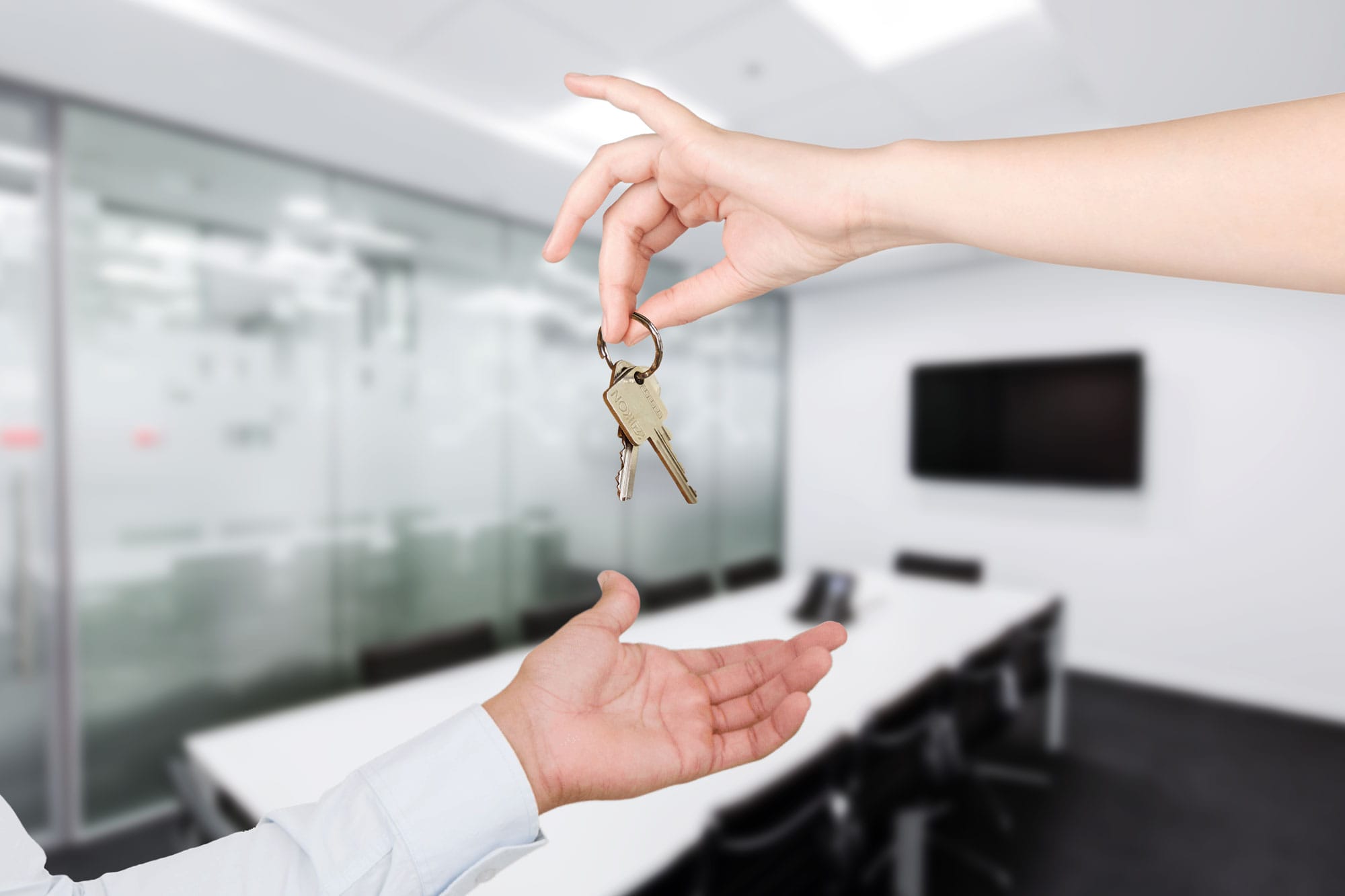 A woman holding a pair of keys over a man's hand to give him