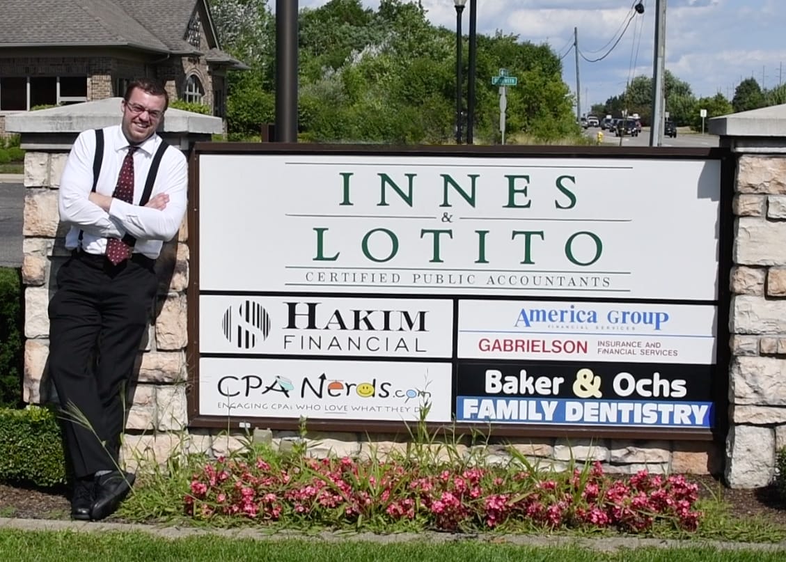 CPA Nerd Brad Chapman standing by the Innes & Lotito, P.C. logo outside of the office