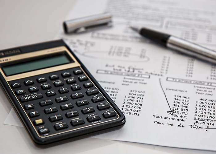 A calculator sitting with a tax document and an uncapped pen