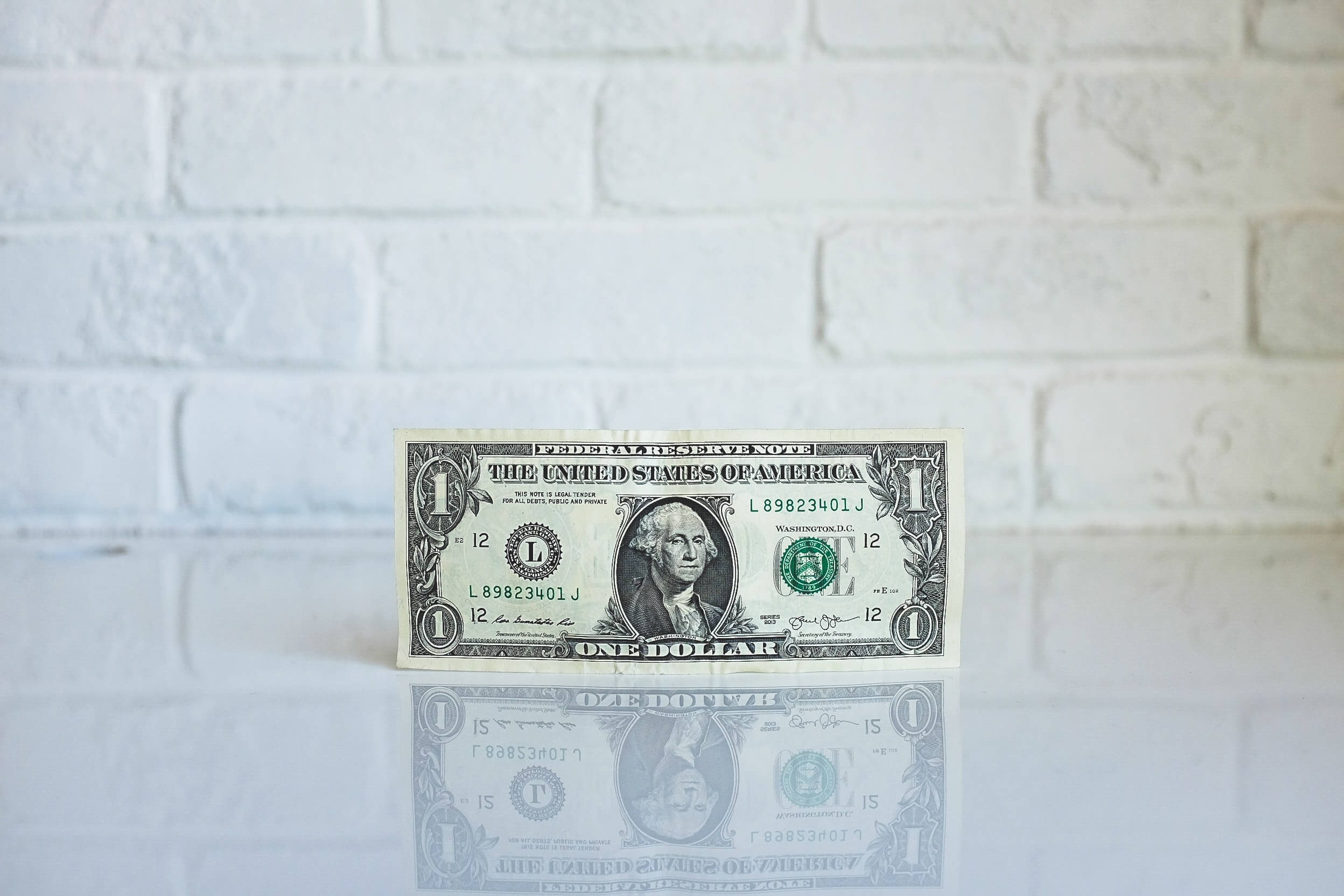One dollar American bill standing up on a flat glass surface