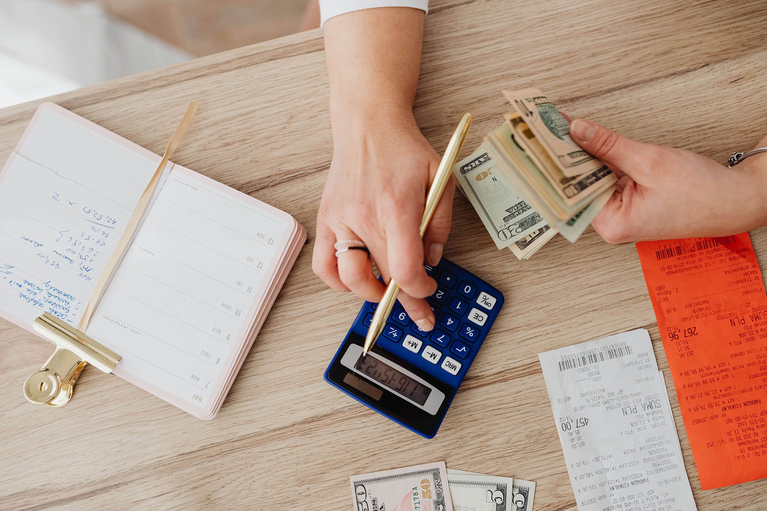 A woman holding money in one hand and typing on a calculator with the other hand