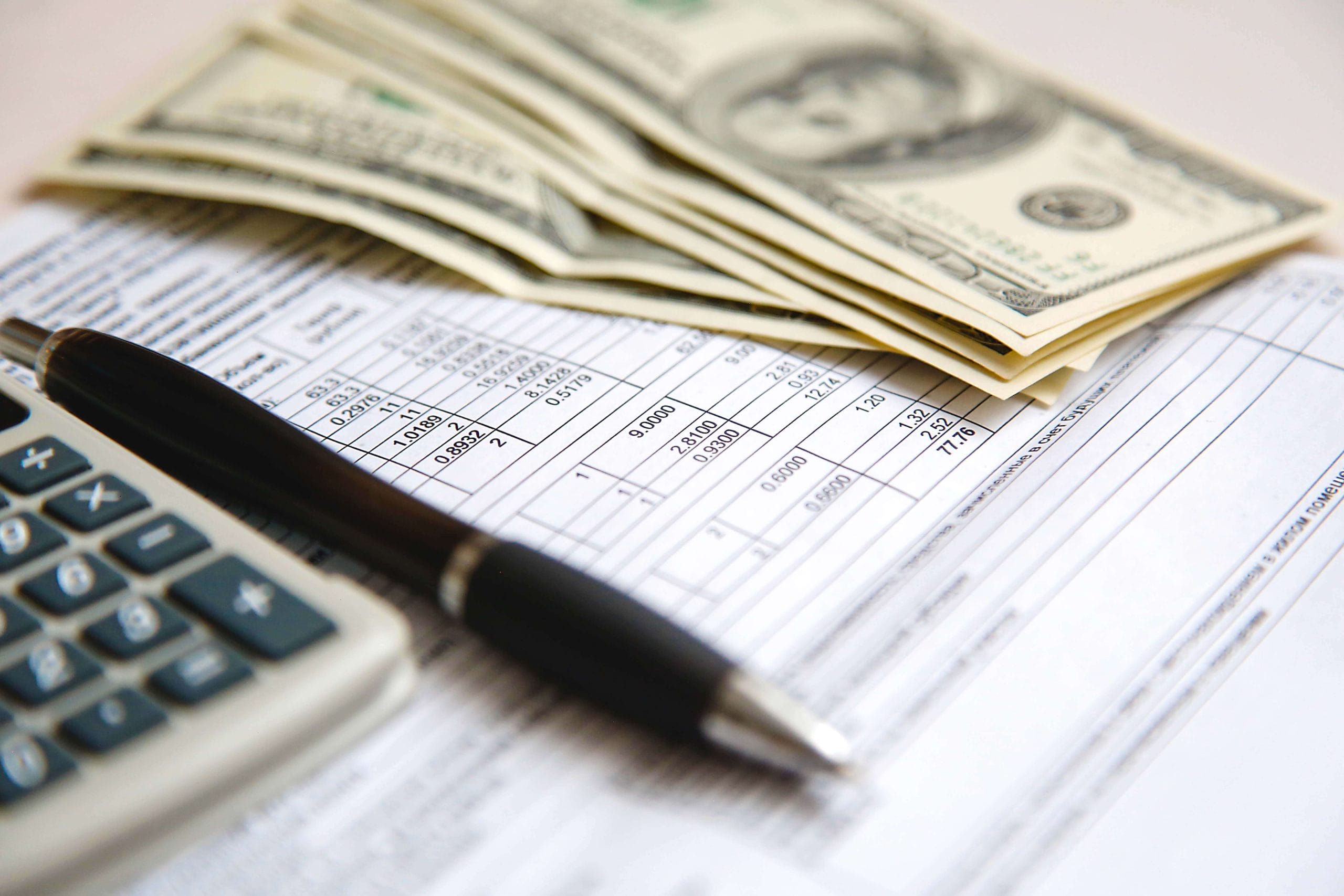 Michigan State Income Tax | Tax form sitting on a table with a pen, calculator, and $100 bills.